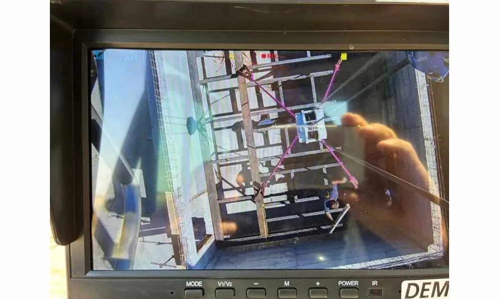 Monitor u kabini autodizalice prikazuje snimak kamere uz kuku tokom spuštanja tereta u dubok betonski lift shaft na gradilištu — autodizalica i mobilni kran Demag AC 40 City 40 tona, bezbedno pozicioniranje tereta, Metal Pro iznajmljivanje dizalice Srem i Mačva