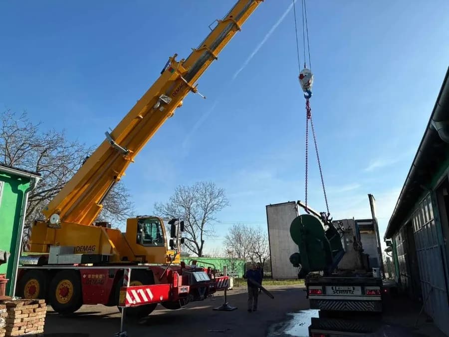 Autodizalica Demag utovara ili istovara tešku industrijsku mašinu sa kamiona pomoću kuke i opreme za dizanje — mobilni kran 40 tona, usluge autodizalice za industriju, Metal Pro Srem Mačva